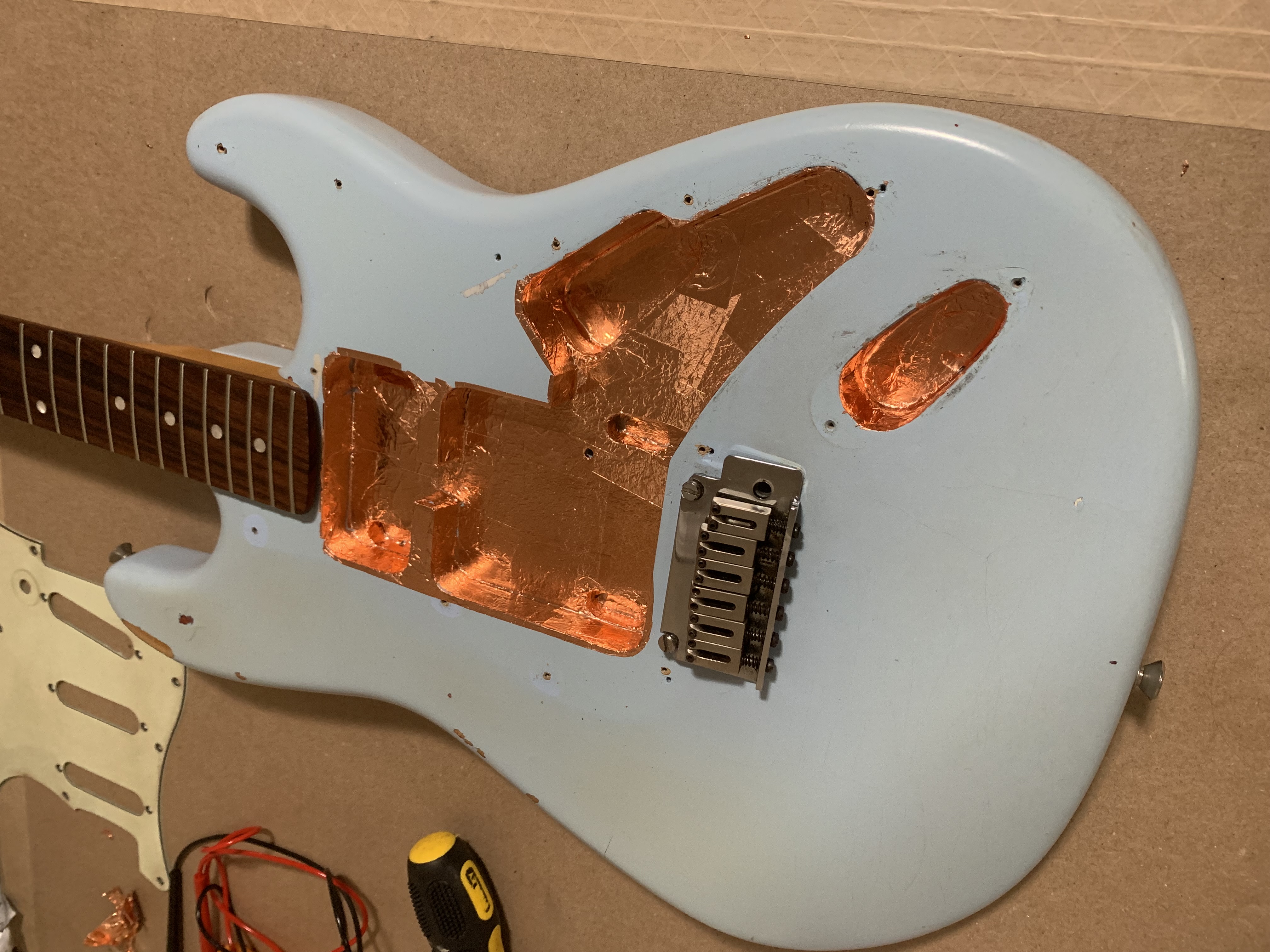 A slightly dismantled guitar on a workbench